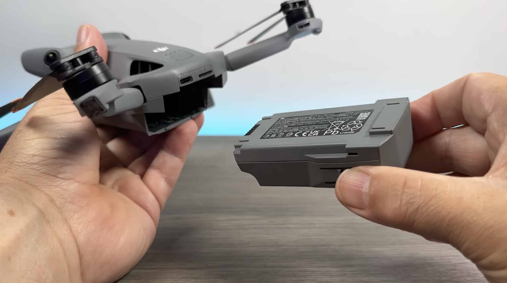 Hands hold the folded drone next to a spare Intelligent Flight Battery.