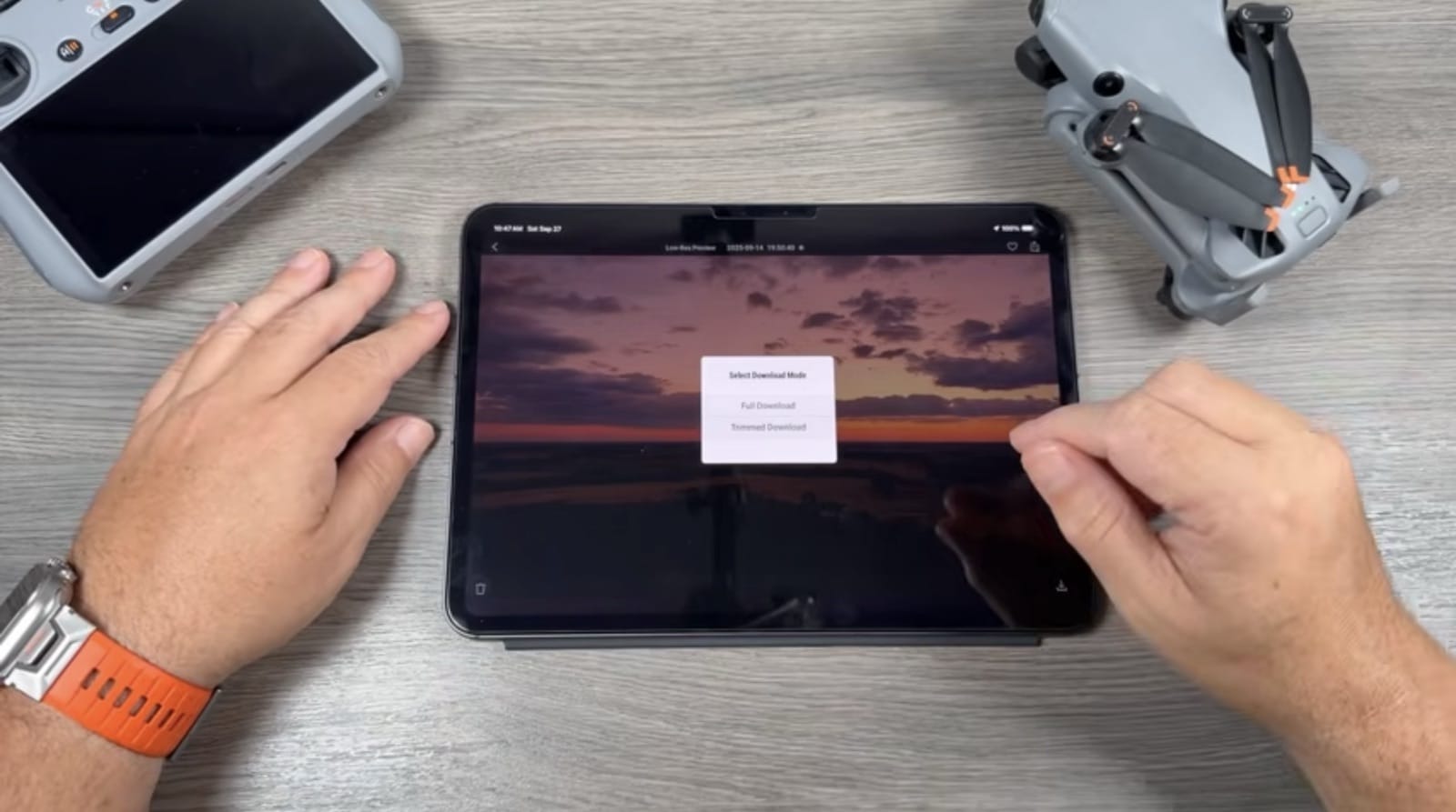 Tablet showing a sunset clip with a small download progress prompt on screen.