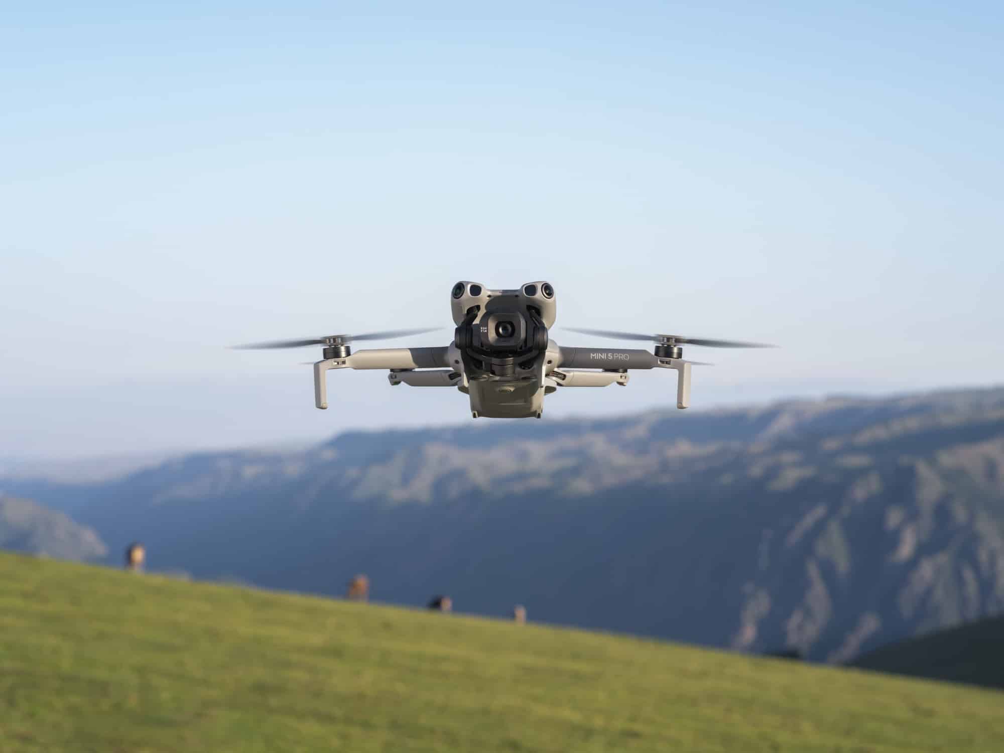 The drone hovers over a sunlit ridge with a deep hazy valley falling away behind.