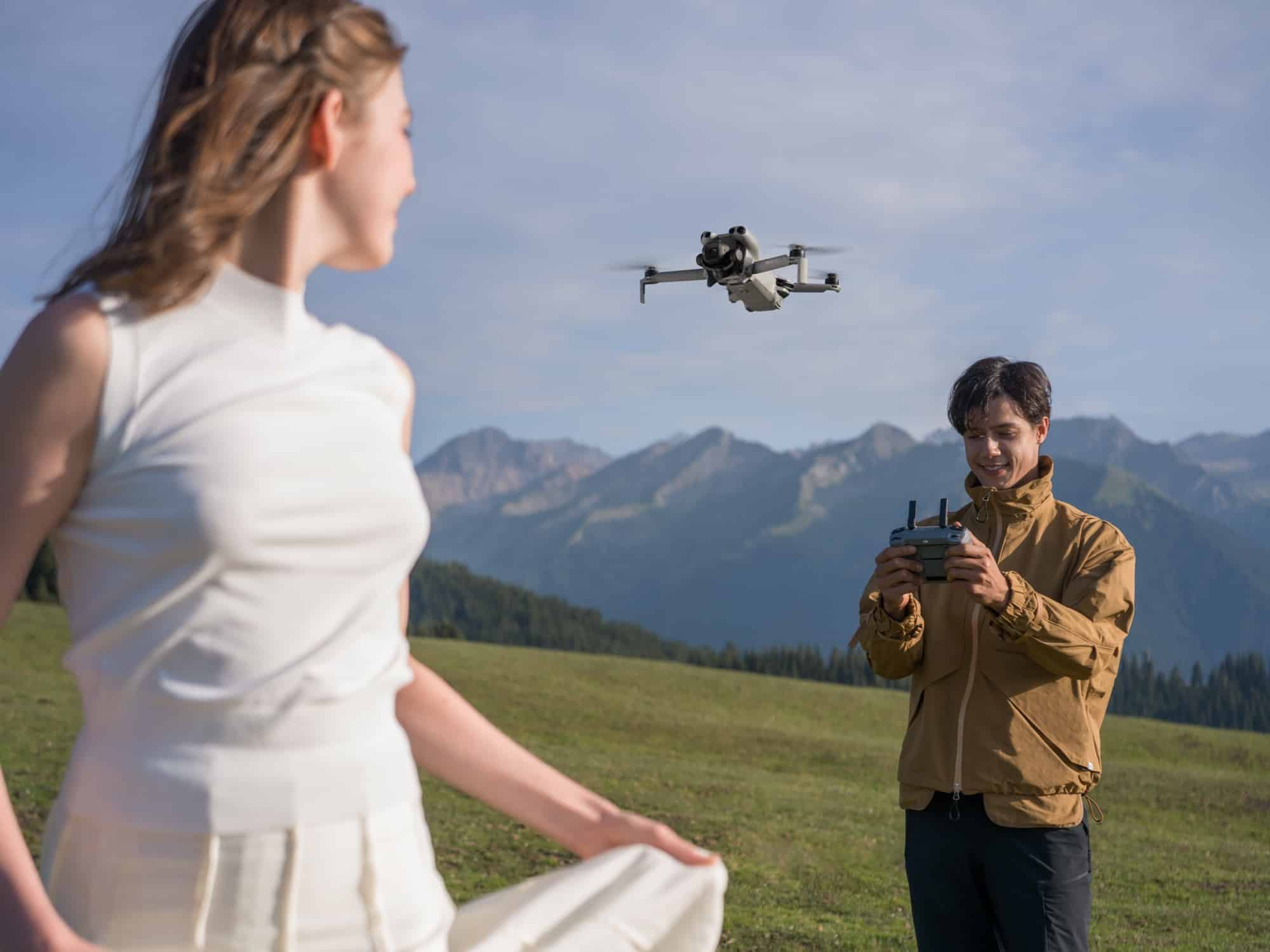 A woman in white walks ahead while a man behind her works the controller.