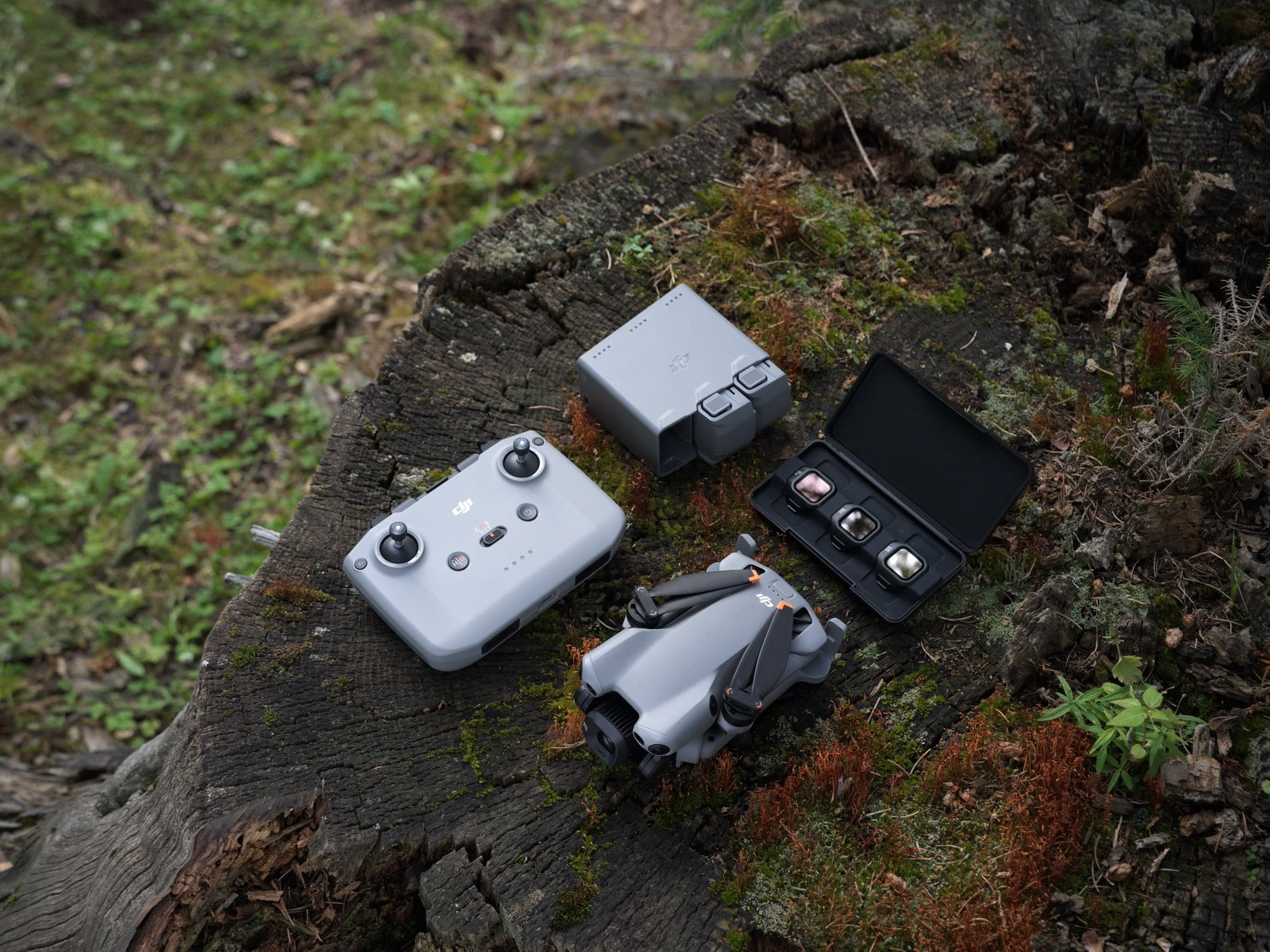 Drone, controller, battery charging hub and a closed filter case on weathered wood.