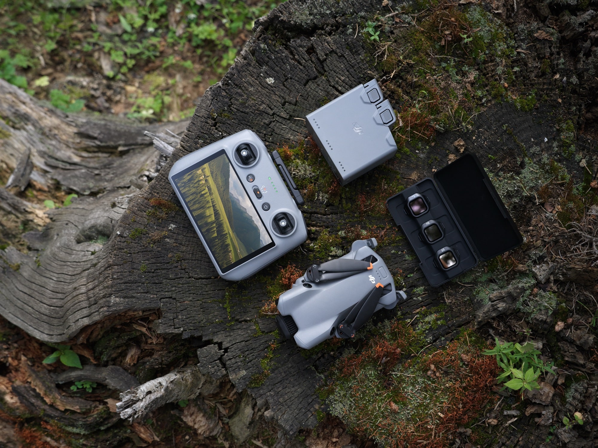 Drone with the touchscreen controller, charging hub and open filter case laid outdoors.