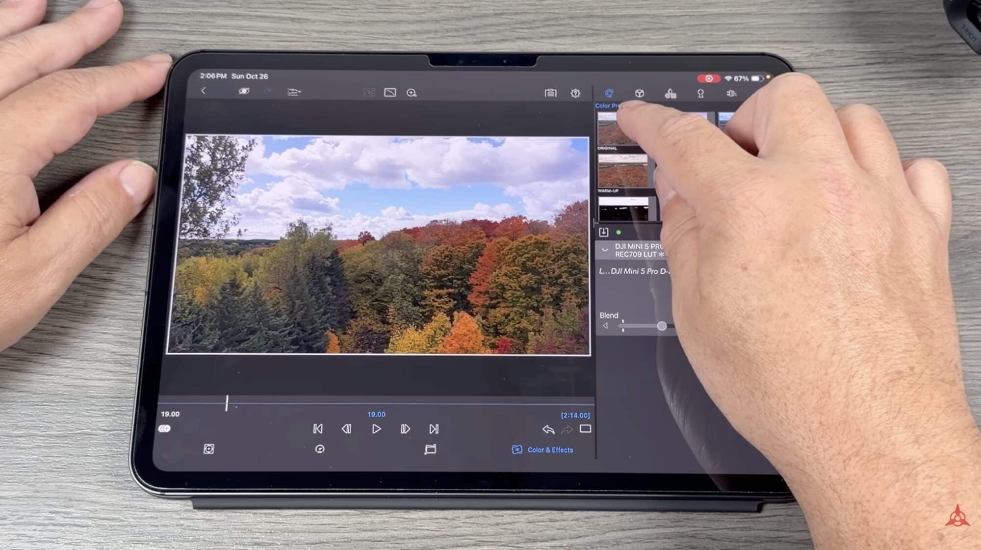 Hands grading autumn forest footage in the DJI Fly editor on a tablet.