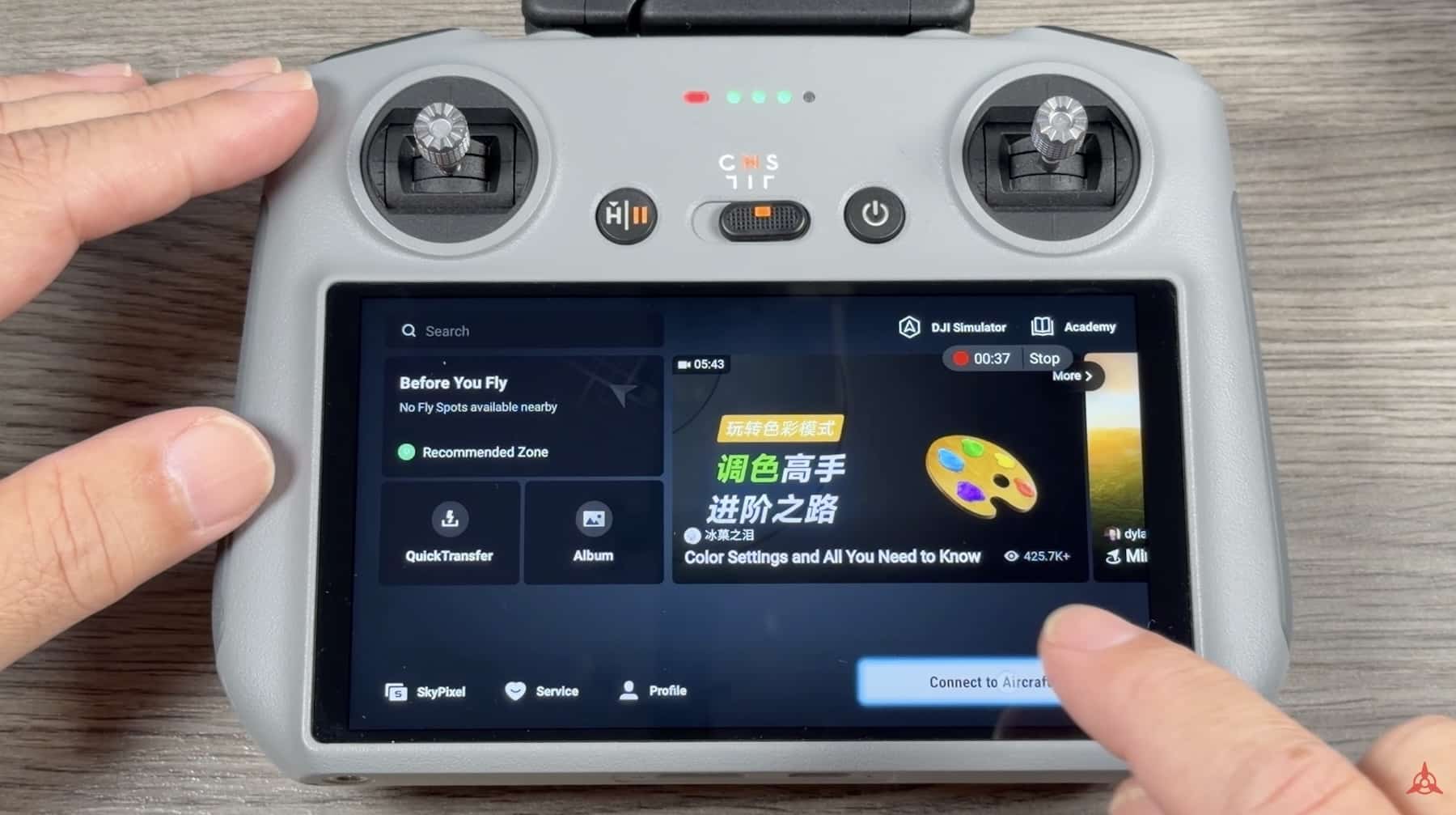 Hands hold a DJI RC 2 controller showing the Fly app home screen.