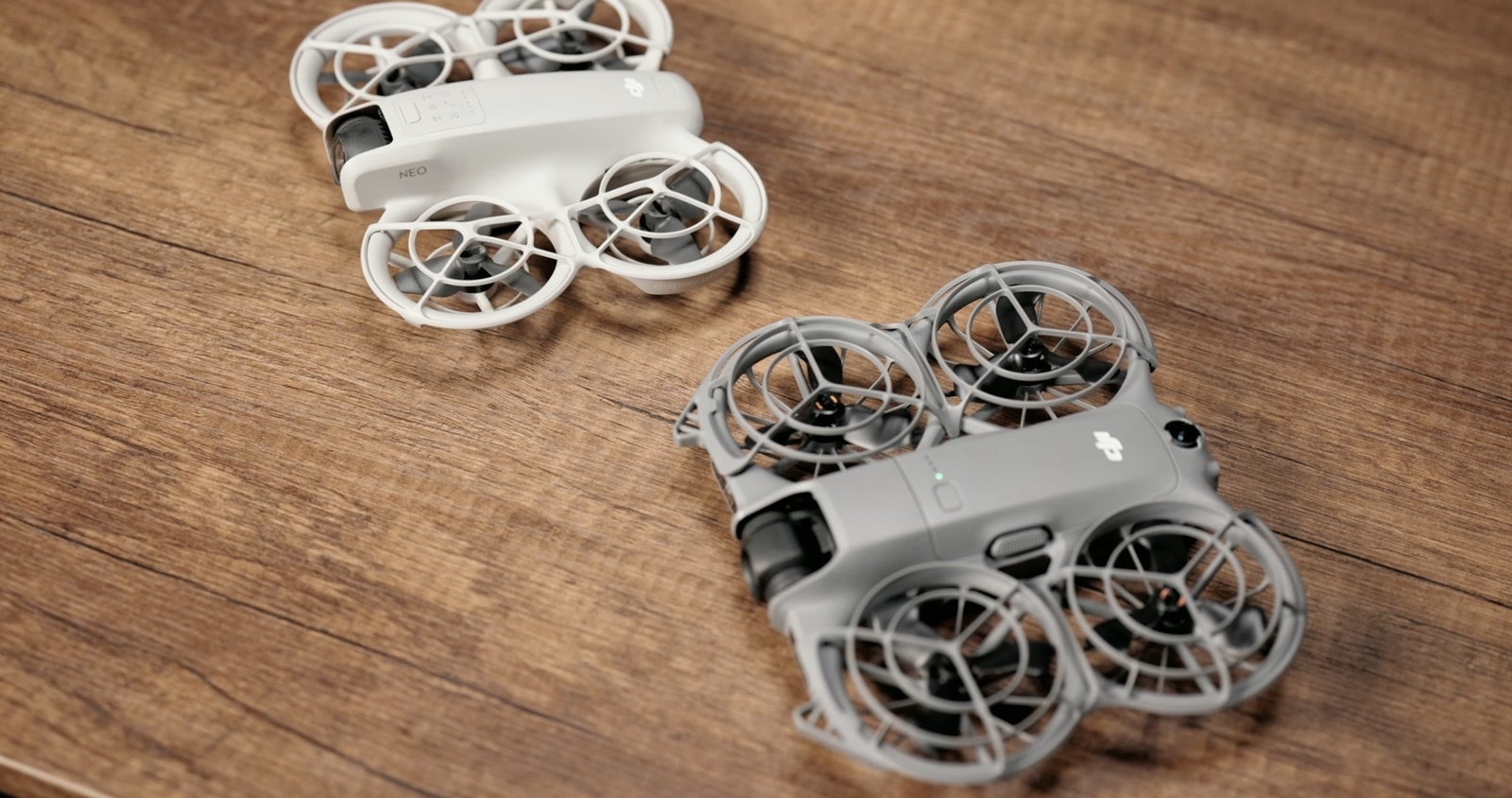 The white original DJI NEO placed behind its darker second-generation successor.