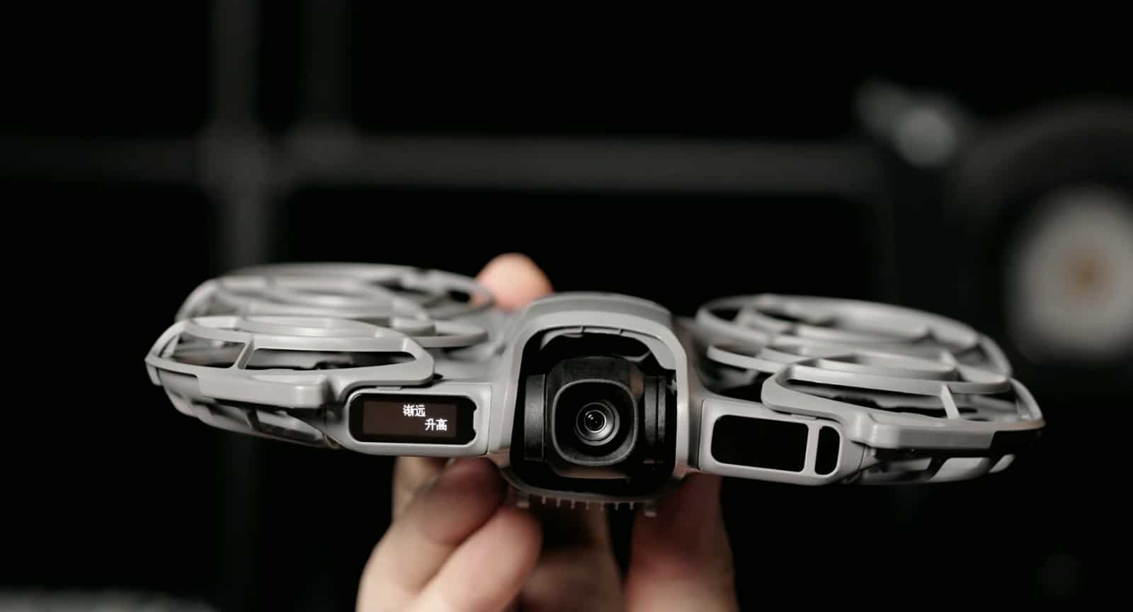 Hands present the drone head-on, the gimbal camera and front display in focus.