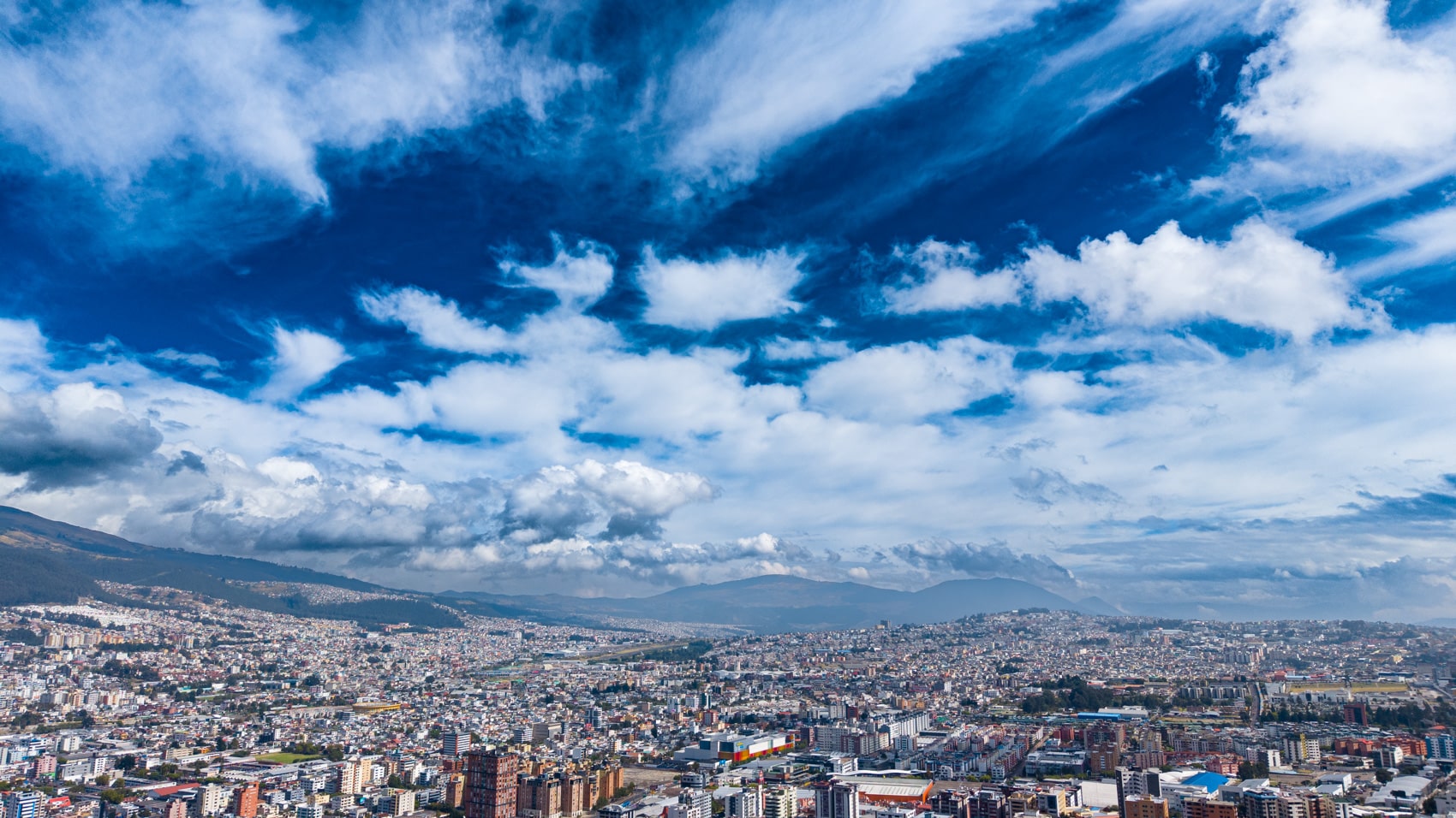 Aerial view of a sprawling city under a dramatic blue sky with clouds.