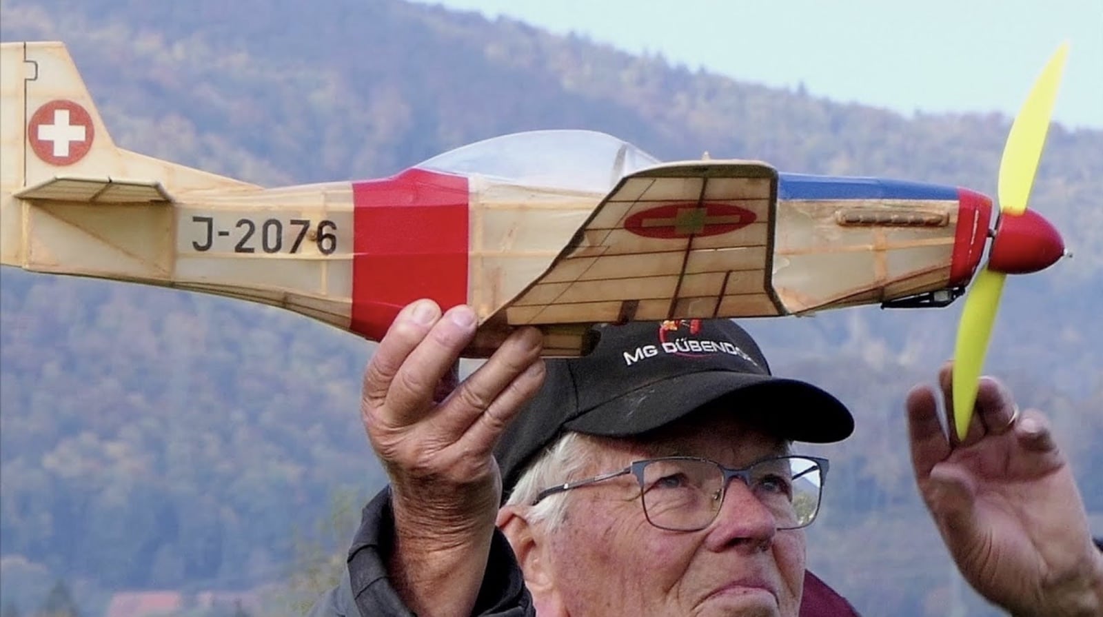 A young flier with a rubber band-powered balsa model at a Swiss free-flight club.