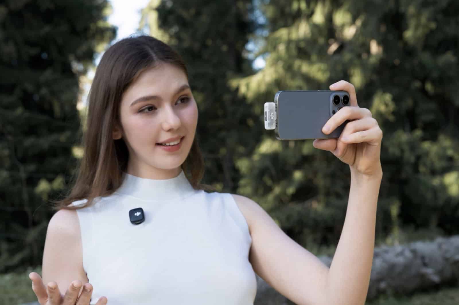 Woman films herself on a smartphone while wearing a DJI wireless microphone transmitter.