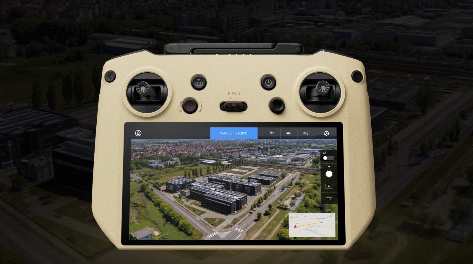 Beige controller displaying an aerial view of an industrial campus on its screen.