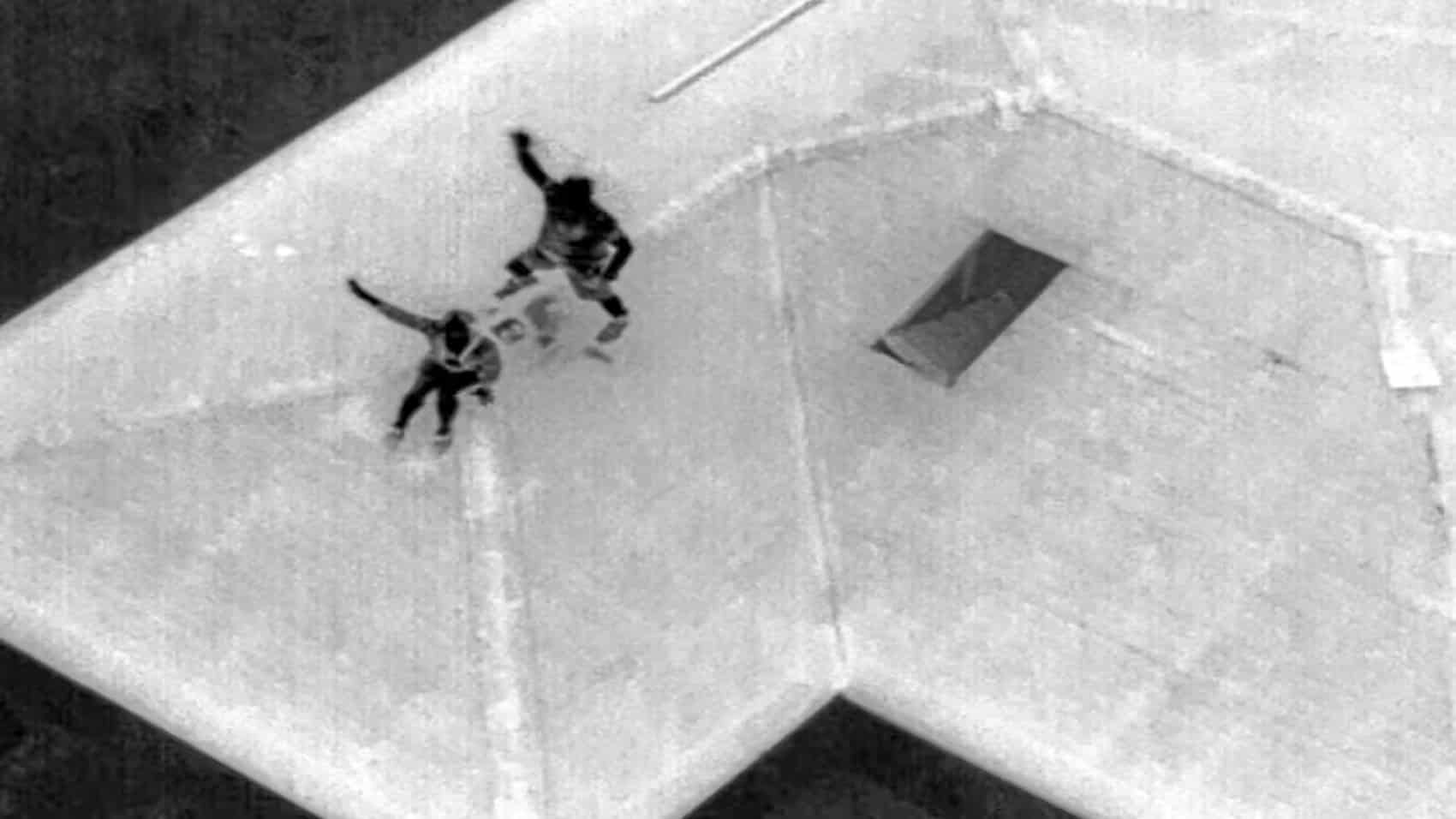 Thermal drone image showing two heat signatures of people on a rooftop.