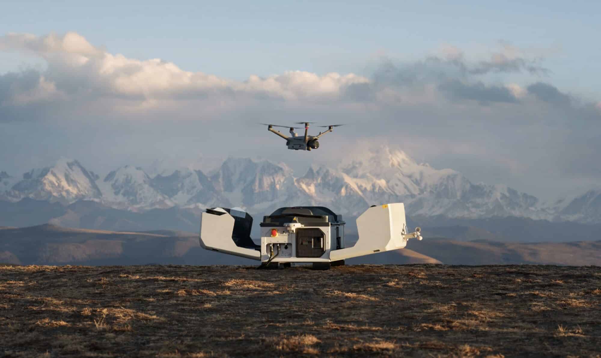 Drone lifting off from an open dock with snow-capped mountains behind.