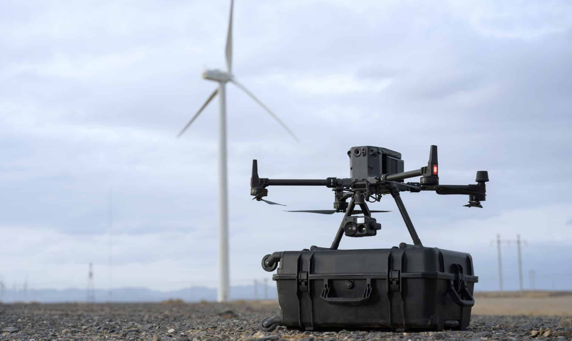 Enterprise drone parked on a hard case with a wind turbine behind it.
