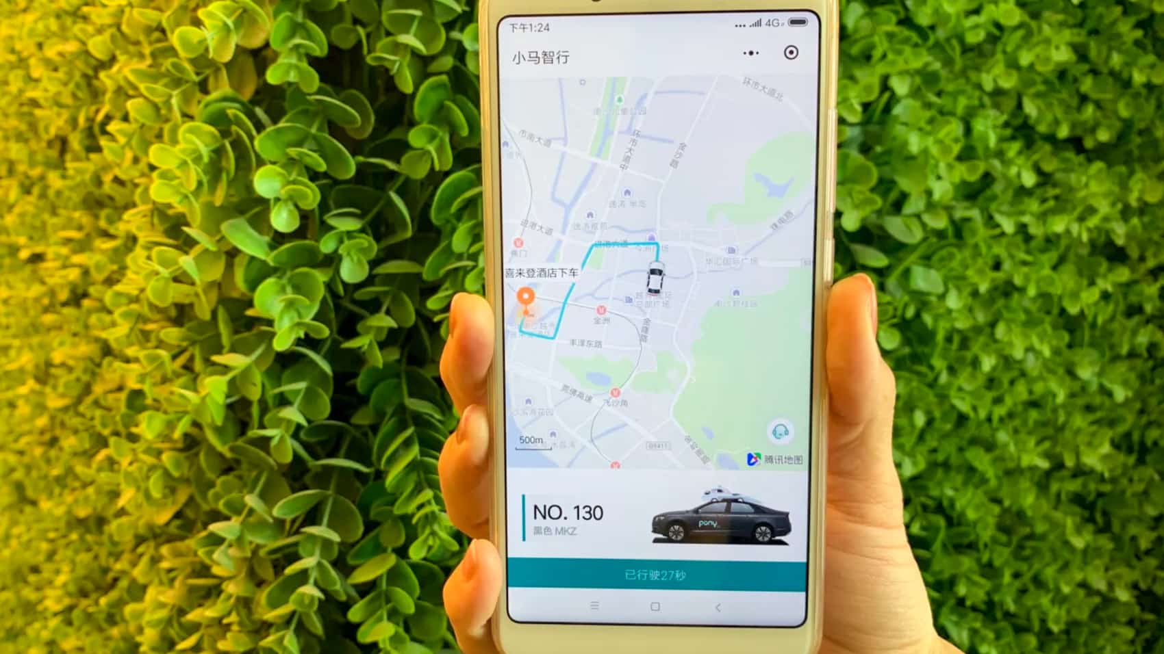 Hand holding a phone showing the Pony.ai app tracking an assigned robotaxi.