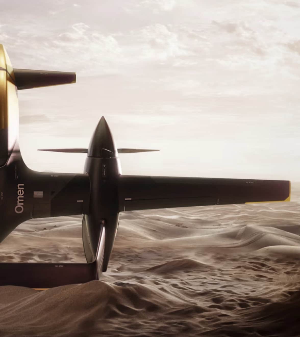 Anduril Omen hybrid VTOL drone flying low over desert dunes.