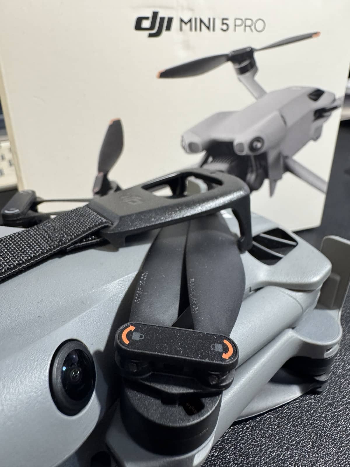 A folded DJI Mini 5 Pro rests in front of its retail box.