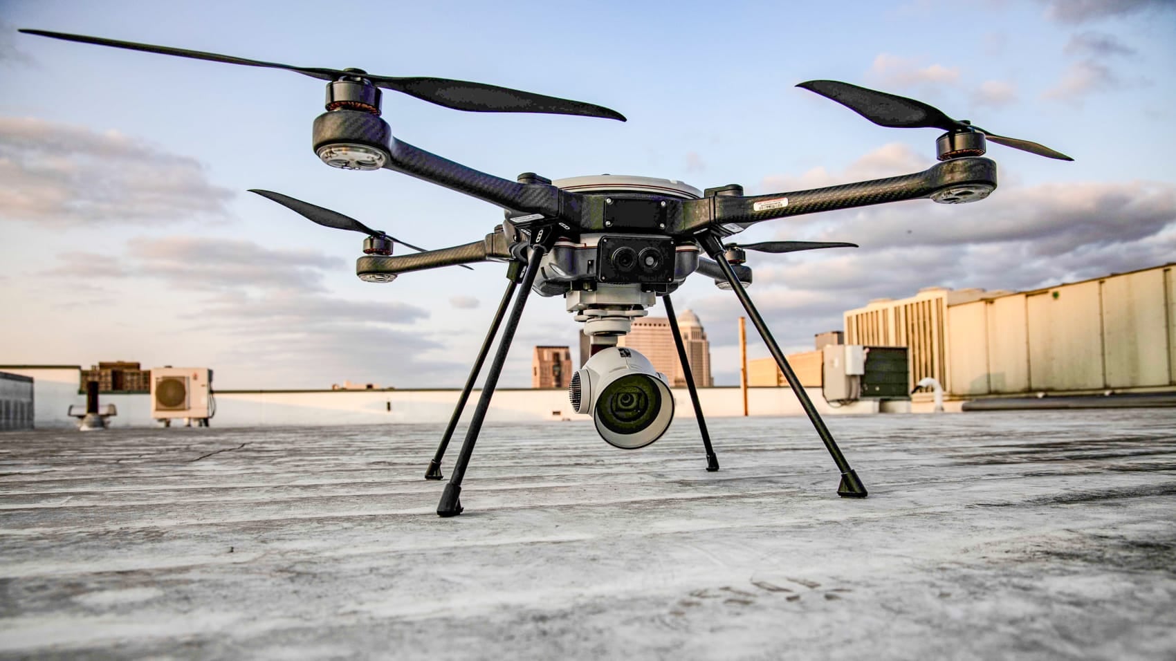 A CBP quadcopter with a gimbal camera parked on a border outpost rooftop.
