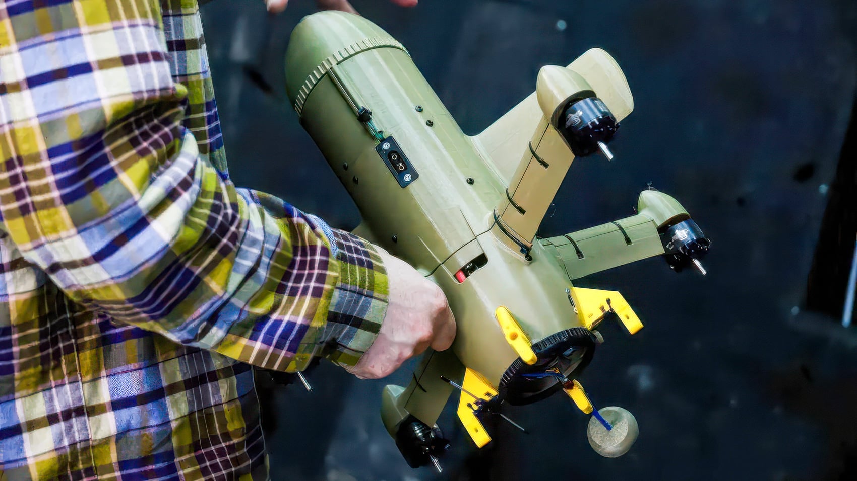 A person carries an olive-green interceptor drone fitted with four electric motors.
