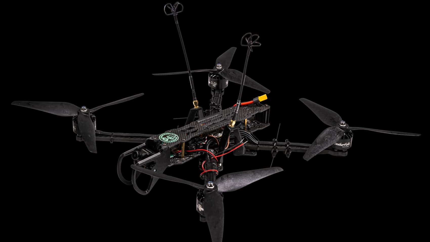 Carbon-fiber quadcopter interceptor with long antennas photographed against a black backdrop.