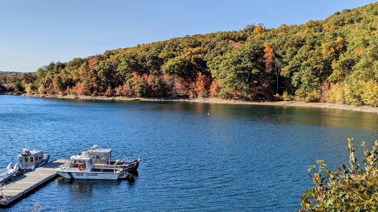 Patrol boats moored at a Quabbin Reservoir dock below autumn woods.
