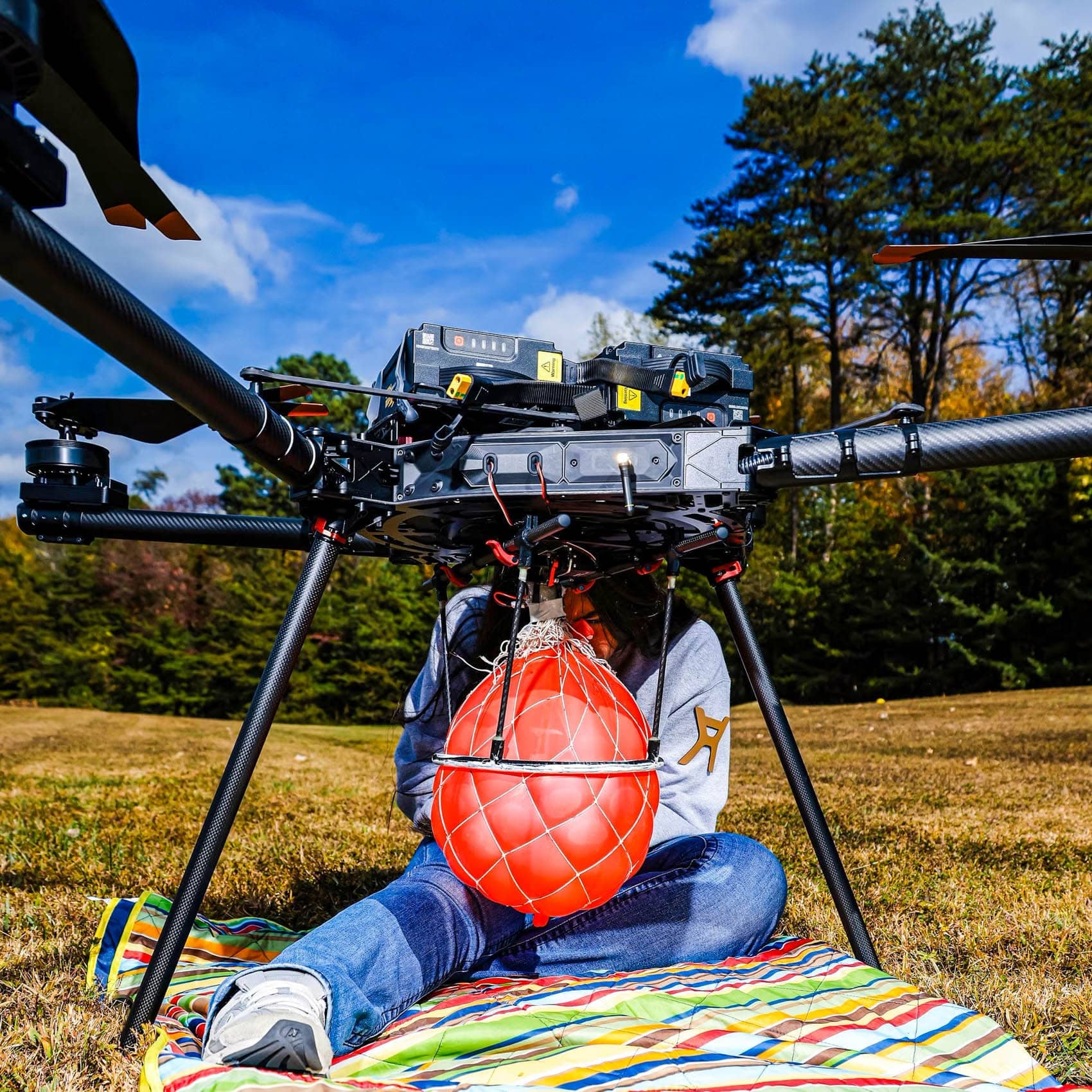 A Freefly Alta X on the grass with a red water balloon slung beneath it.