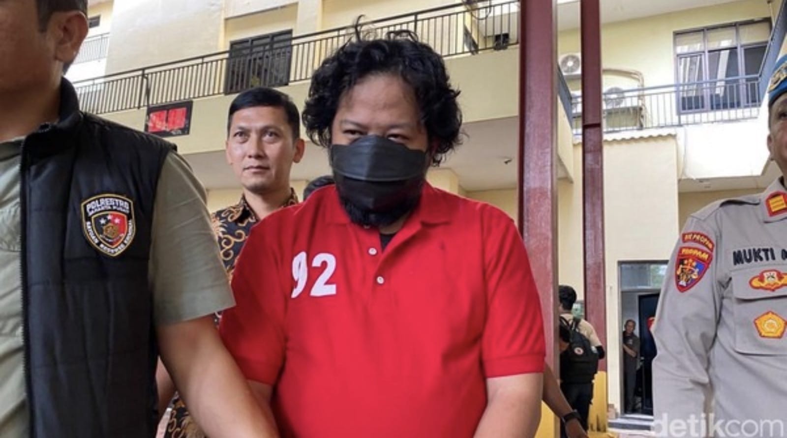 Indonesian police escort the arrested Terra Drone Indonesia chief executive in a red polo shirt.