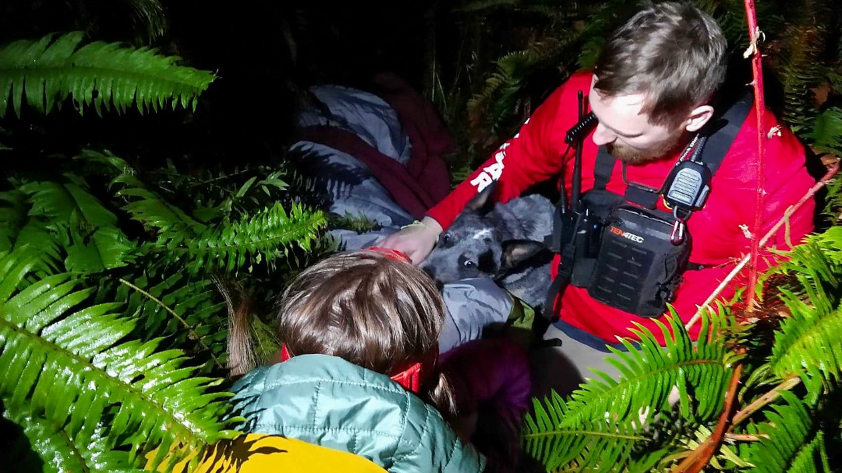 Crews carry the hiker in a rescue basket toward the waiting ambulance.