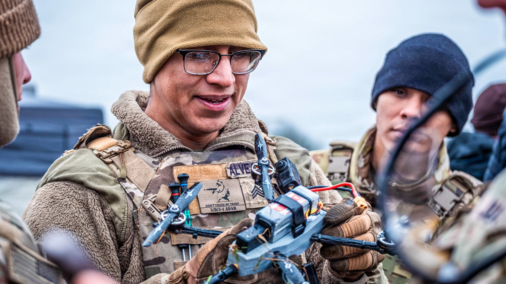 A soldier holds an FPV quadcopter while briefing teammates at the Flytrap exercise.