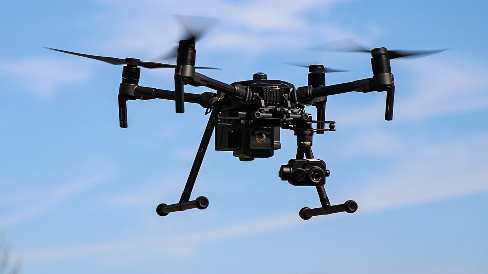 DJI Matrice 210 airborne with thermal and zoom cameras mounted underneath.