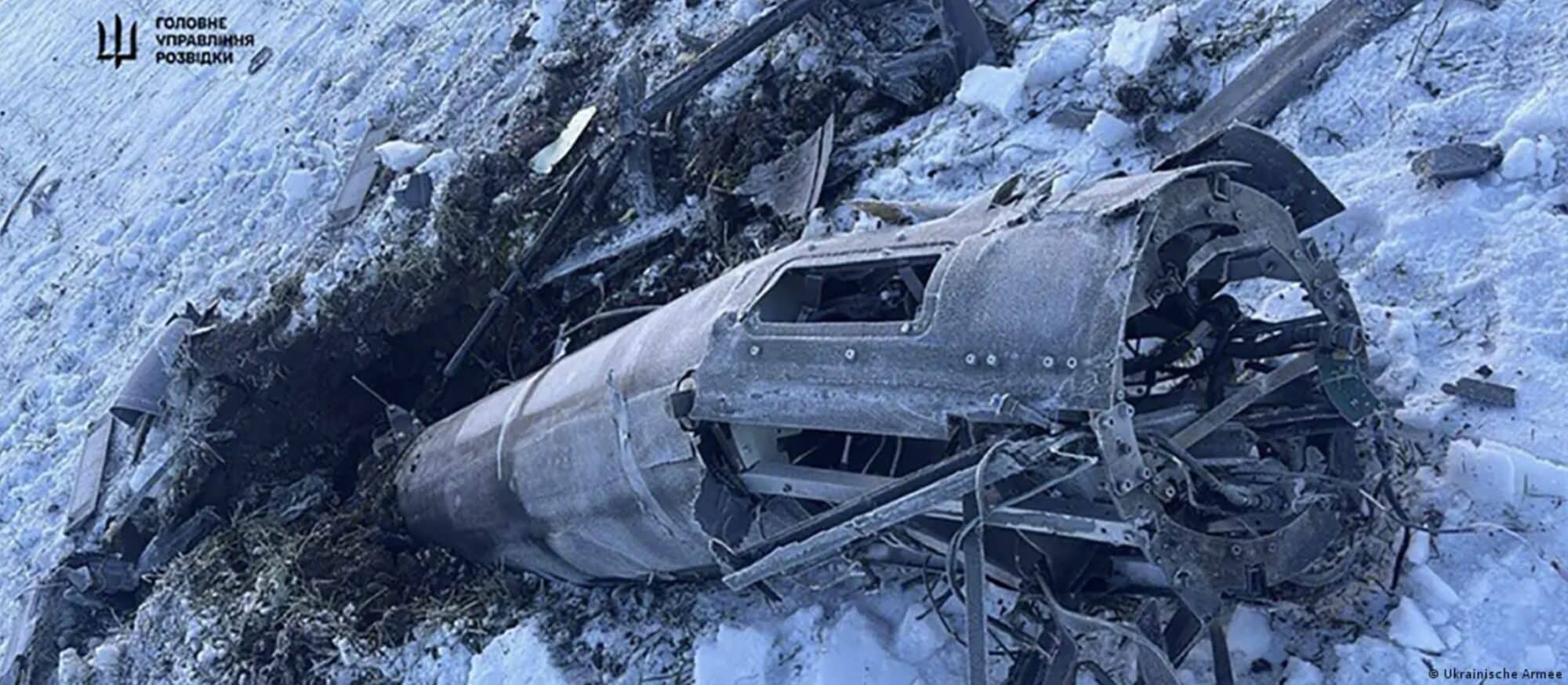 Wreckage of a downed strike drone lying in snow.
