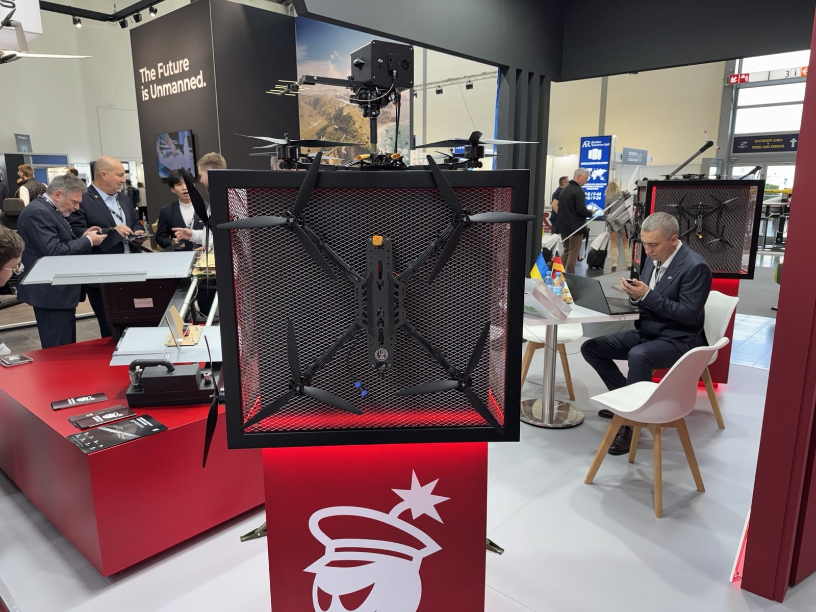 Caged interceptor quadcopter displayed on a red plinth at the General Cherry trade show stand.