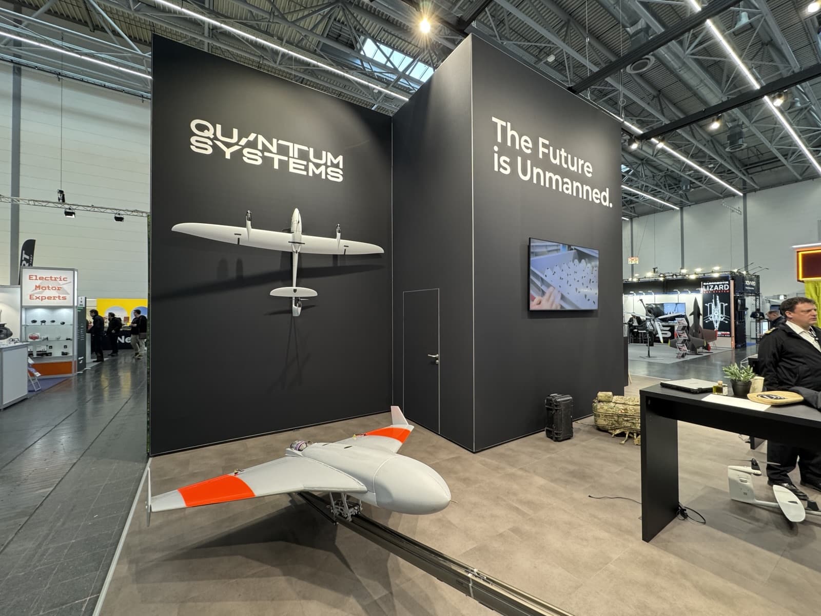 Fixed-wing drone on show at a Quantum Systems booth under an unmanned future slogan.