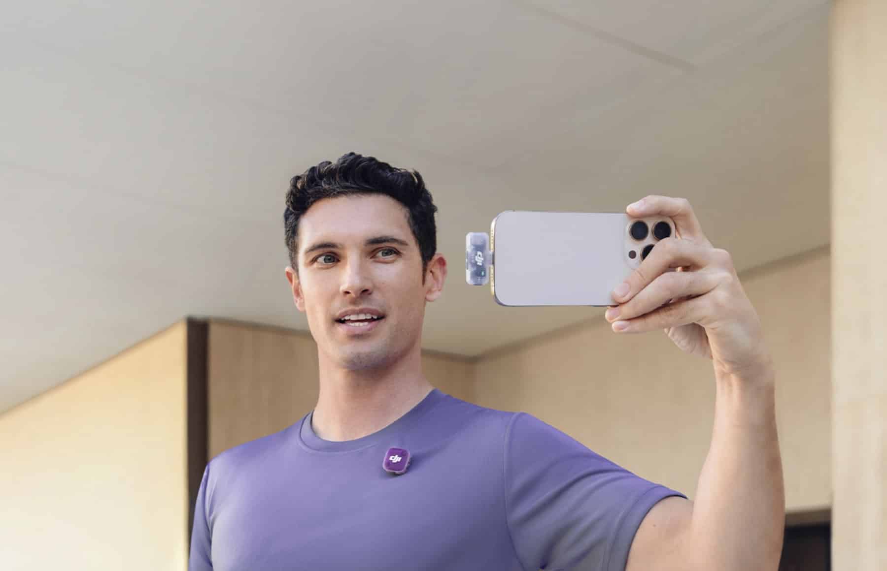 Creator filming a phone selfie video with a magenta Mic Mini 2 clipped to his shirt.