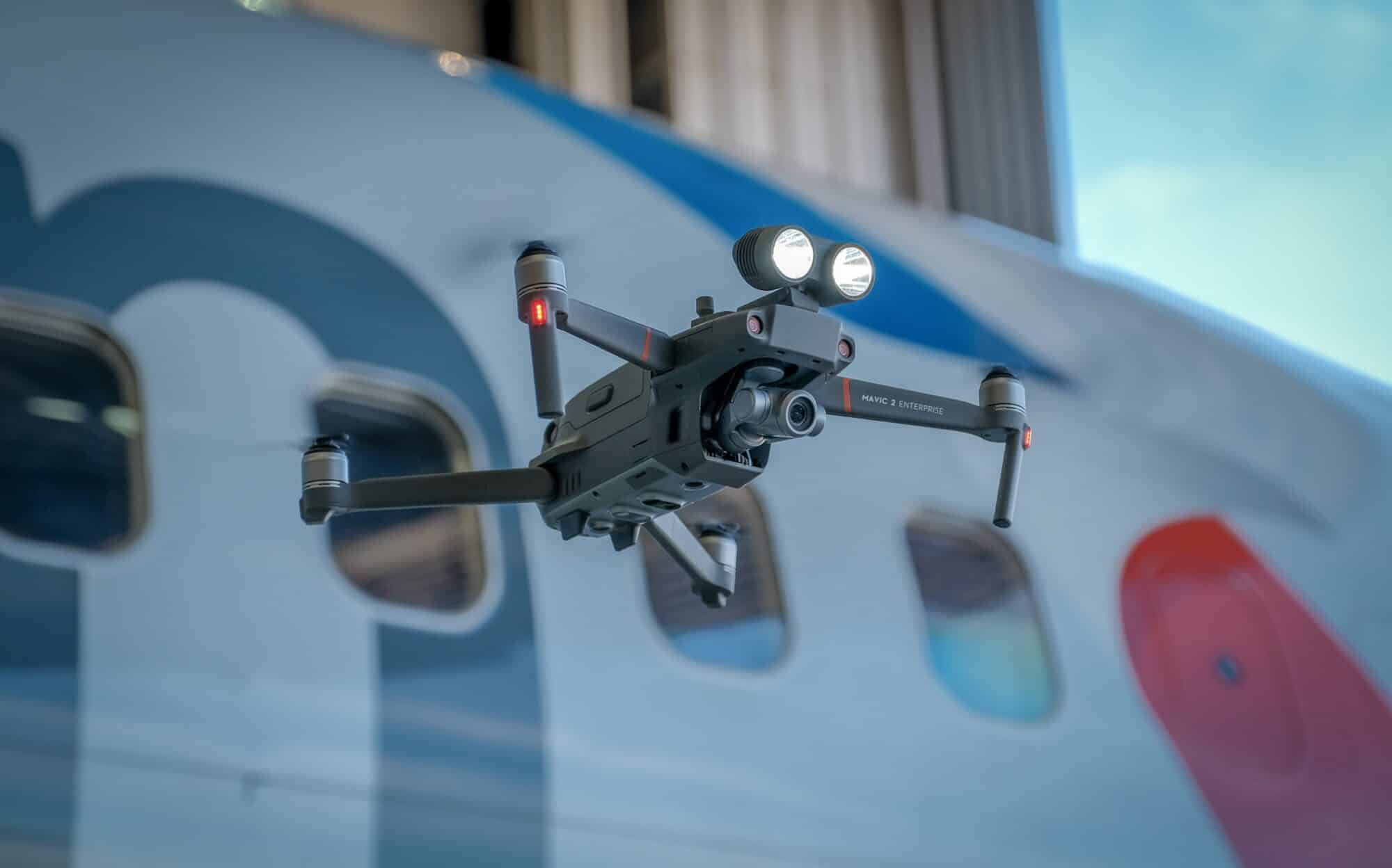 DJI Mavic 2 Enterprise drone at a demonstration from DJI during the DJI Airworks event in 2018 at the Dallas-Forthworth Airport in Texas with an American Airlines plane in the background.