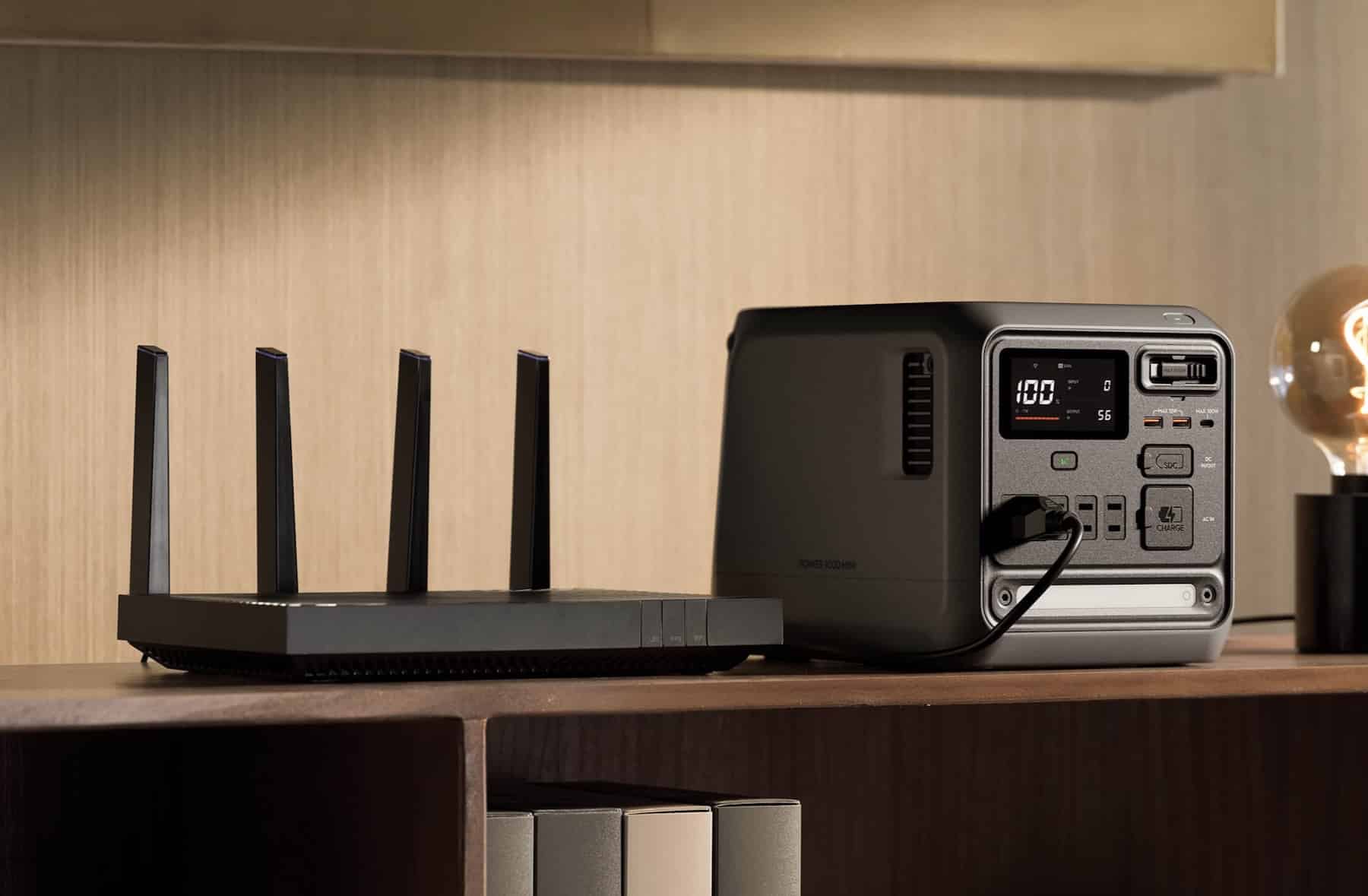 The DJI Power 1000 Mini sits on a shelf beside a black Wi-Fi router.