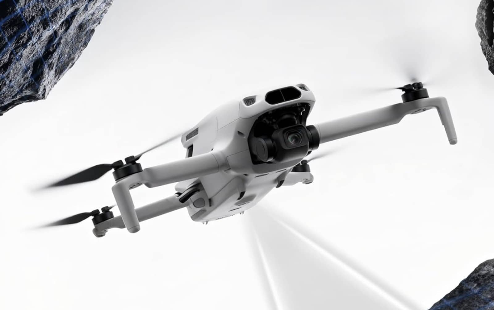 White foldable camera drone in flight between two floating rocks on a white background.