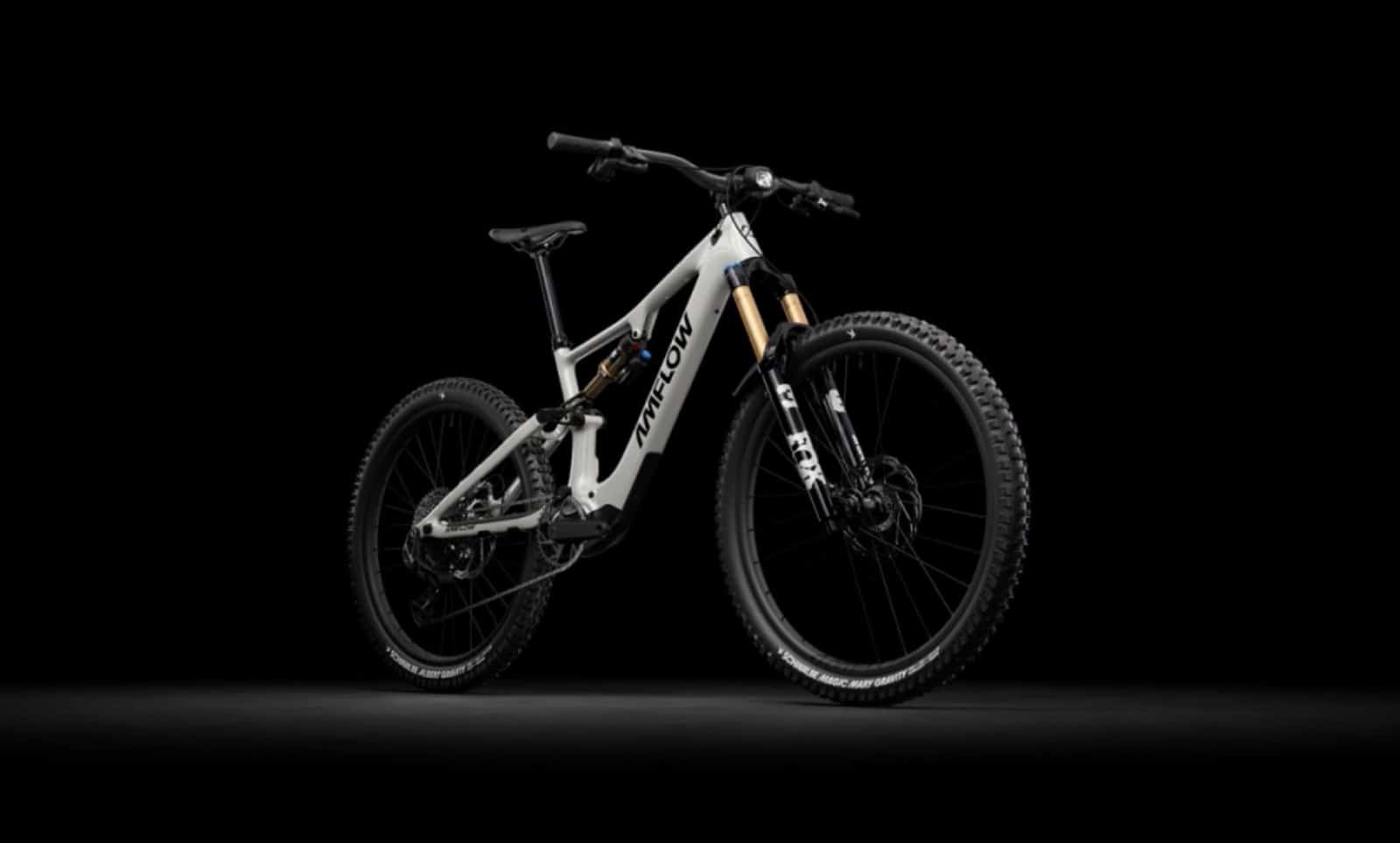 White Amflow full-suspension electric mountain bike photographed against a black backdrop.