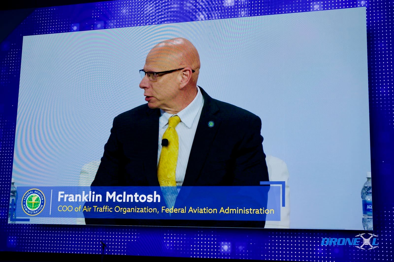 FAA Air Traffic COO Tells XPONENTIAL: 'We See Drones As Aircraft, Operators As Pilots'. Onstage screen at XPONENTIAL Detroit identifying Franklin McIntosh, COO of Air Traffic Organization, FAA, and Jessica Jones, Executive Director, Office of Advanced Aviation Technologies, FAA. 