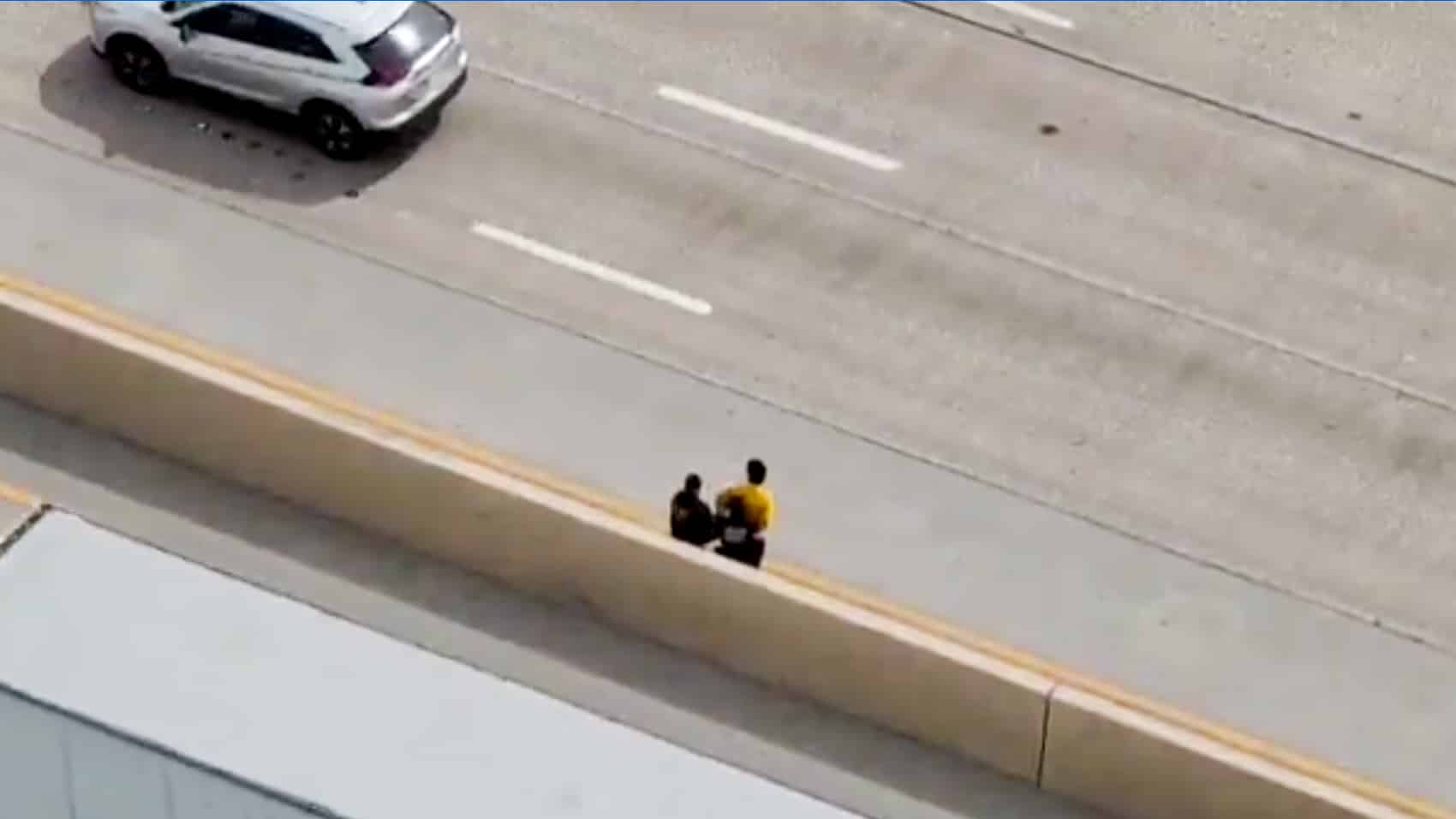 Dallas officers reaching the man on foot and walking him off the freeway.