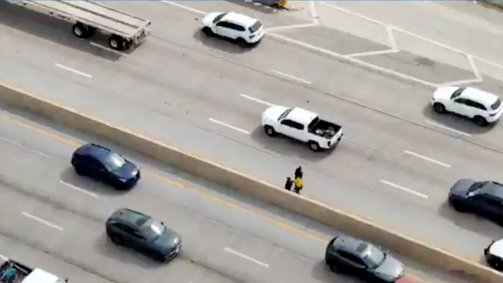 Aerial drone view tracking the man as freeway traffic closes at 65 mph.