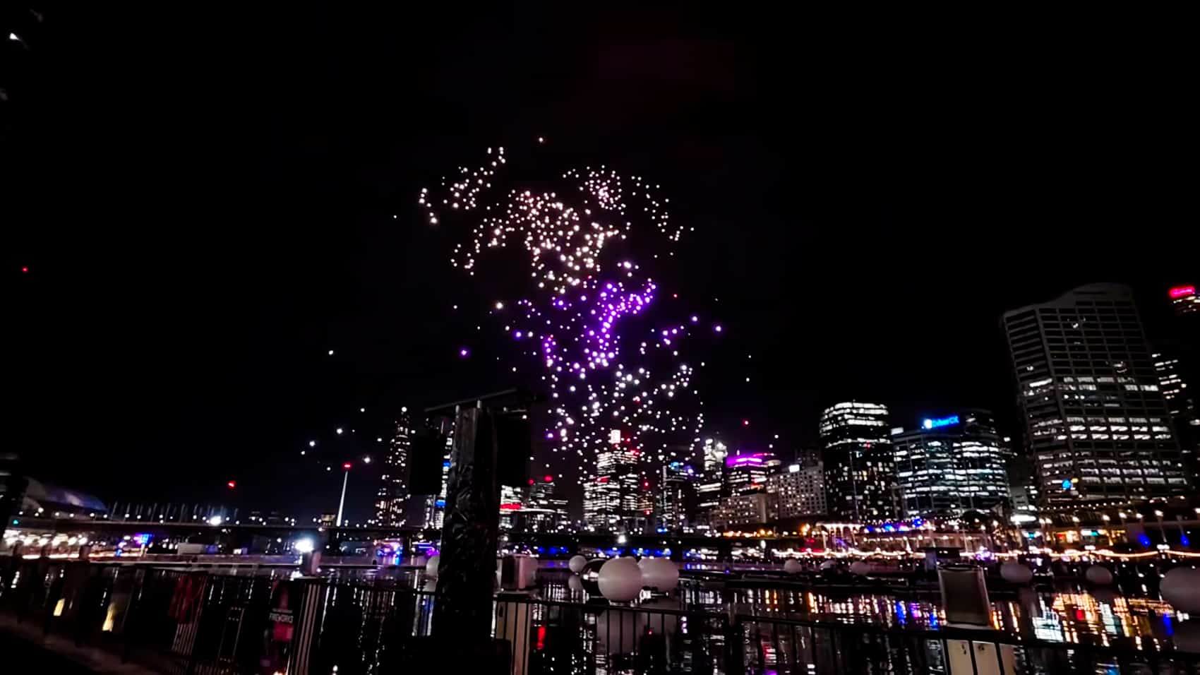 Spectators watching the Vivid Sydney drone display from the harbour foreshore.