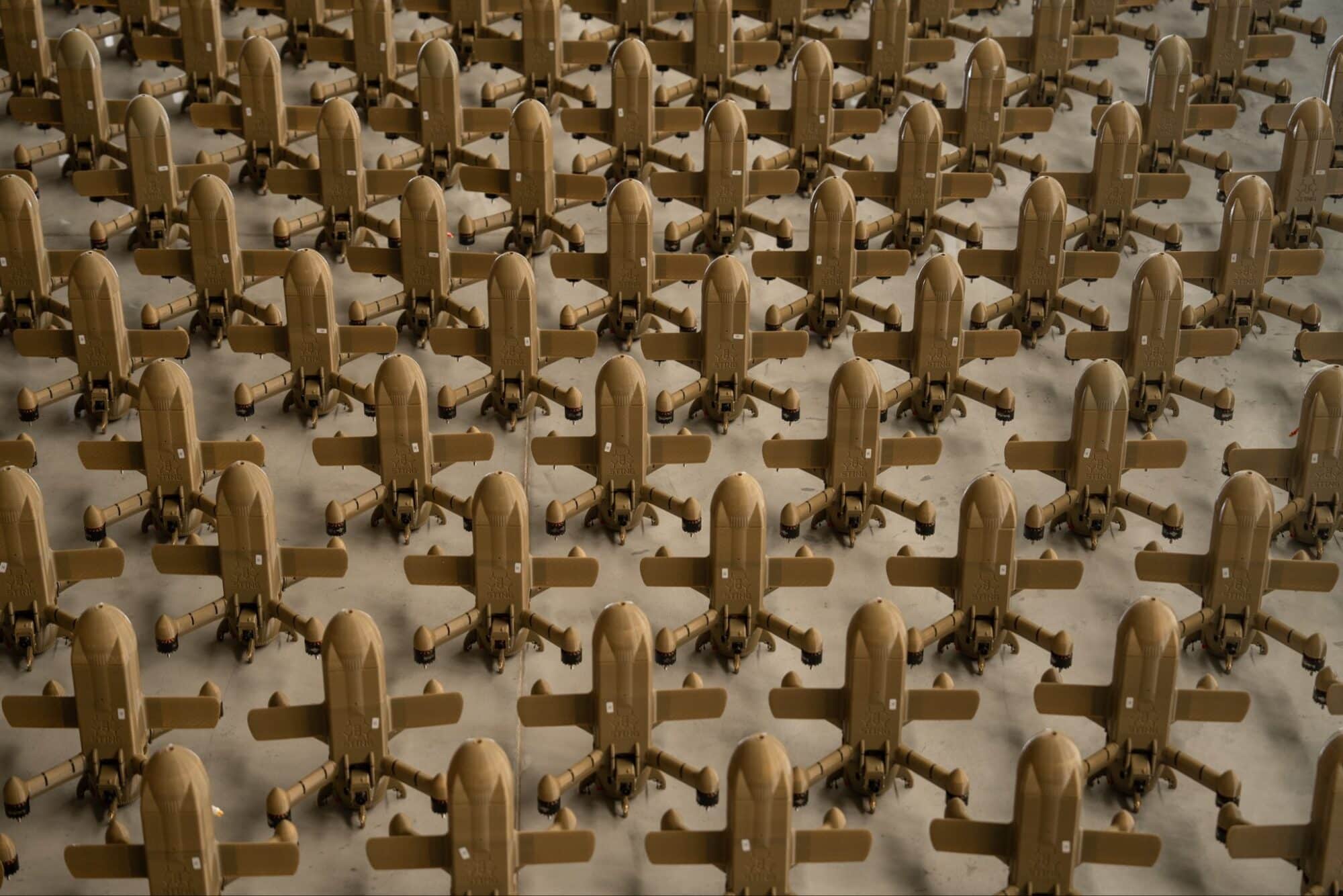 Overhead view of dozens of tan interceptor drones parked in tight rows.