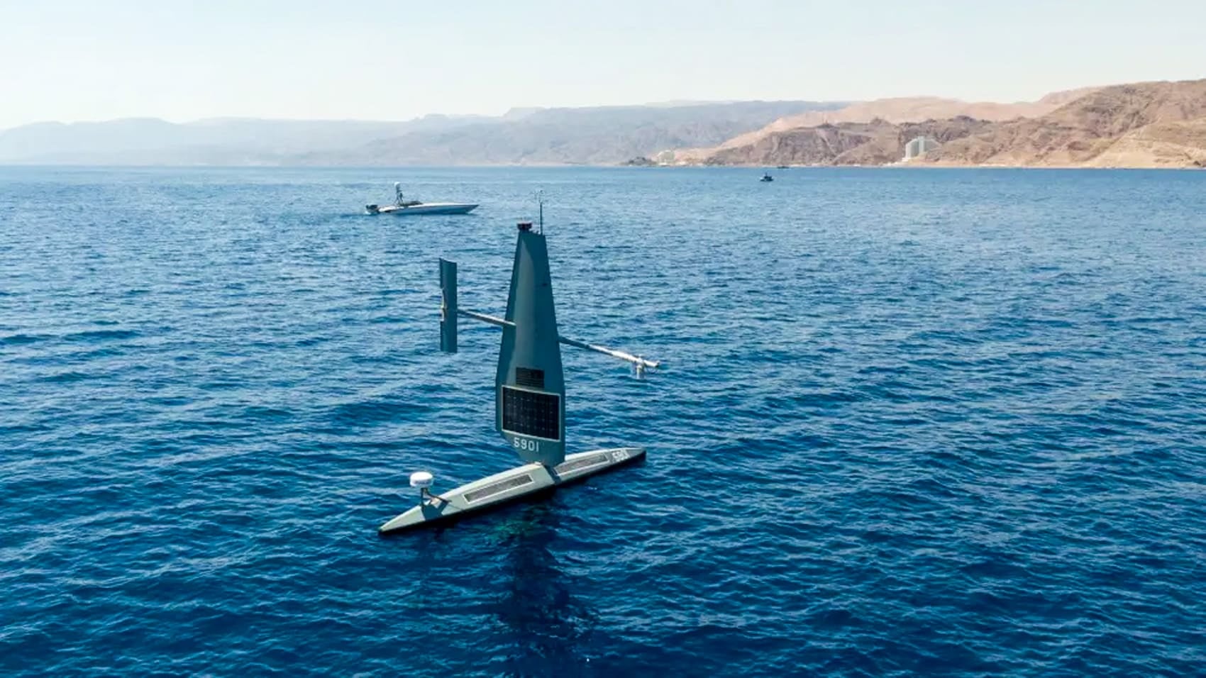 Saronic Corsair uncrewed surface vessel underway on open water near coastal hills.