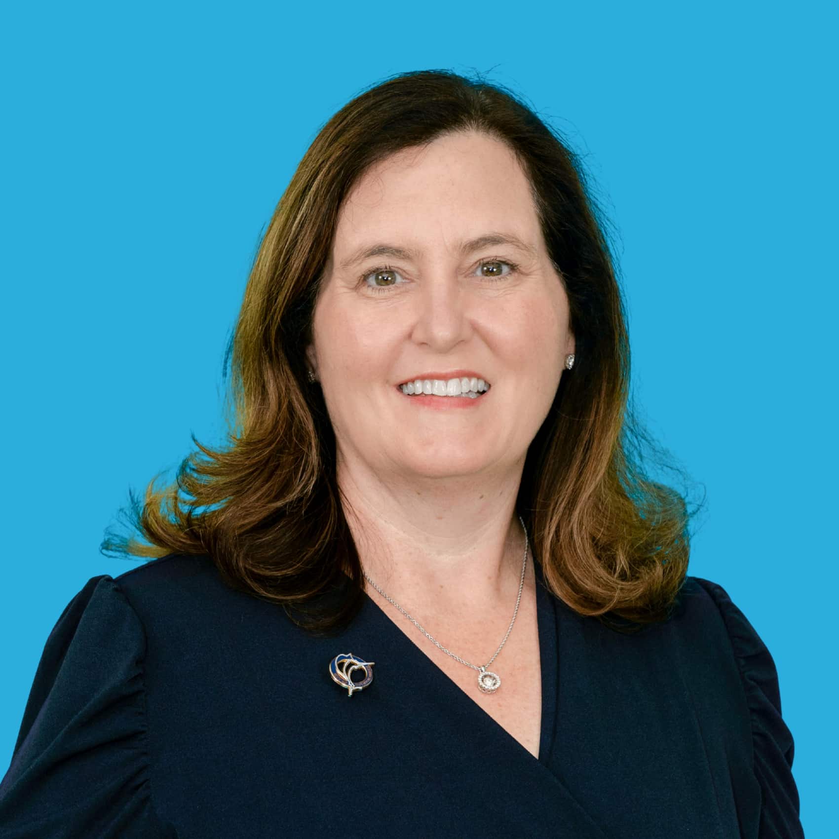 Commissioner Aimee Kelley in an official city portrait against a bright blue backdrop.