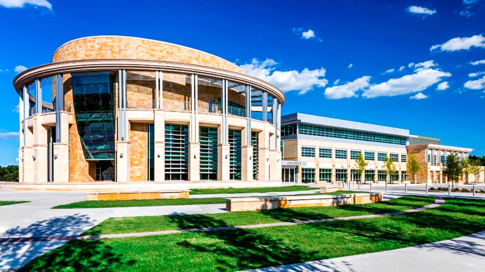 A modern city hall building with a rotunda and lawn under blue sky.