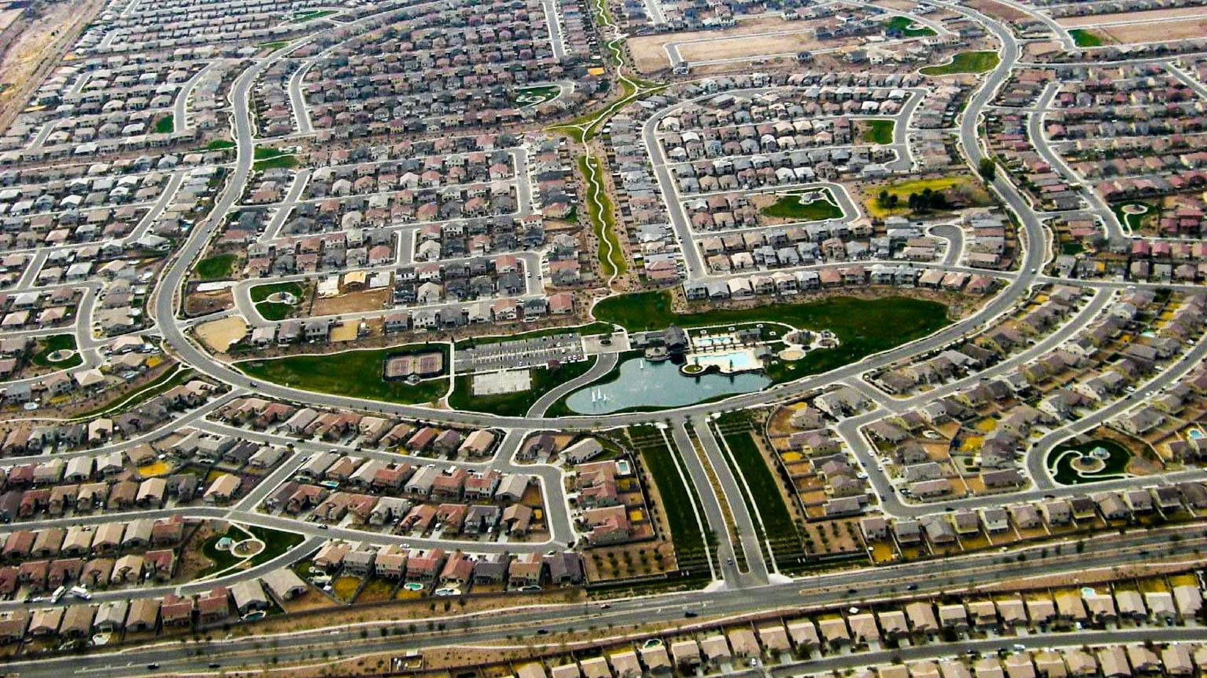 Aerial view of a sprawling Arizona subdivision with curving streets and a lake.