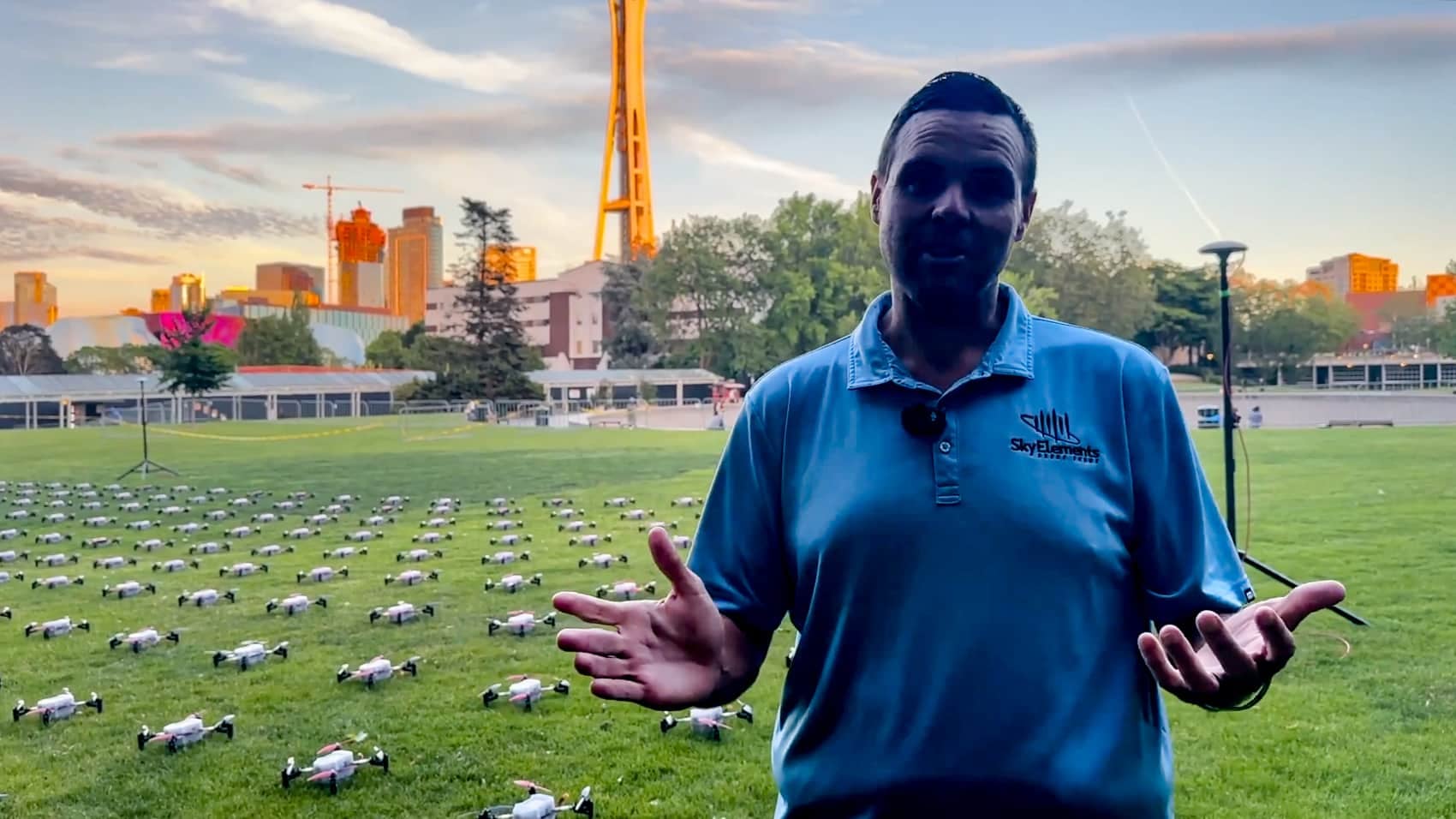 Drone show operator standing before rows of light show drones on a field.
