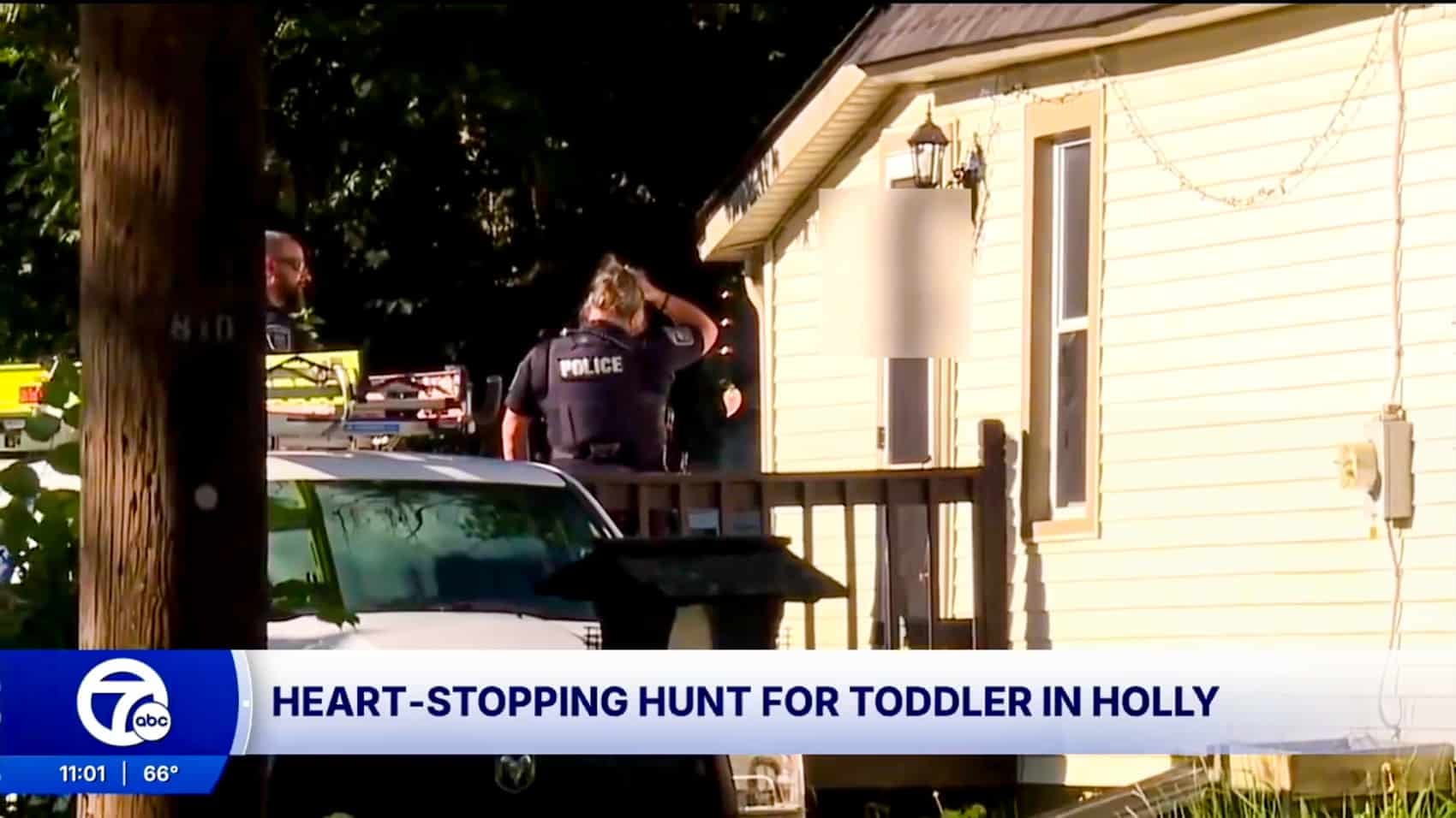 Holly police officers stand outside a home during the search, in WXYZ Detroit footage.