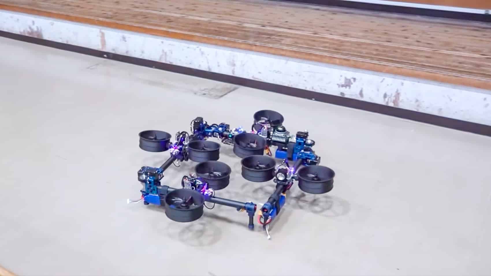 DRAGON drone bent into a boxy configuration just above an indoor floor.