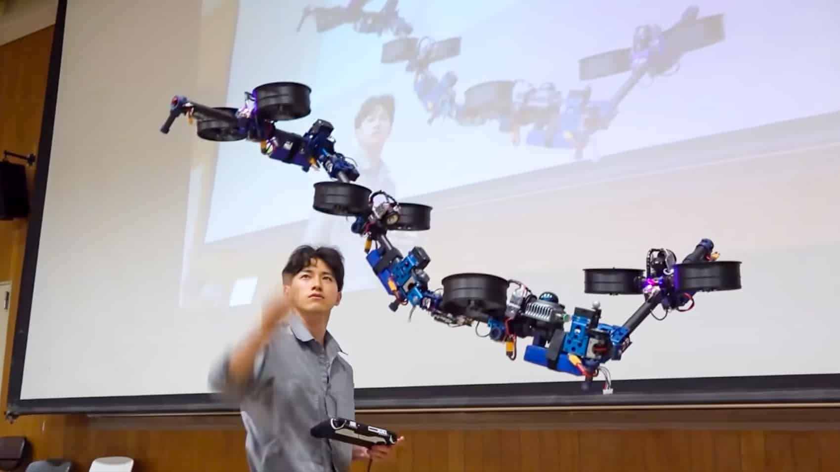 Researcher flies the shape-shifting DRAGON drone in front of a lecture-hall screen.